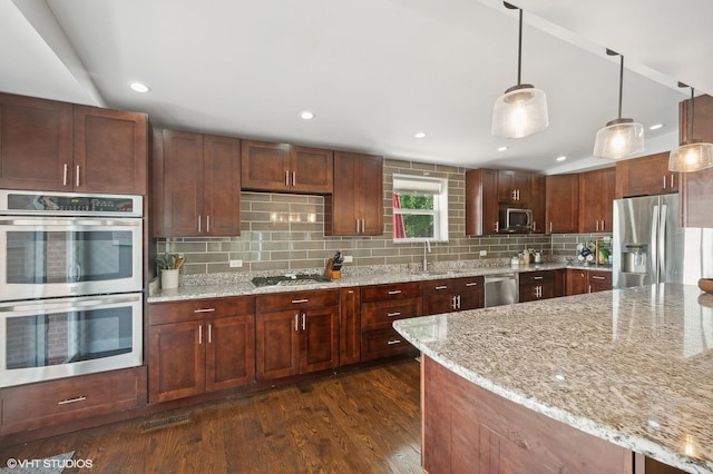 kitchen featuring appliances with stainless steel finishes, backsplash, dark wood-style floors, and light stone countertops