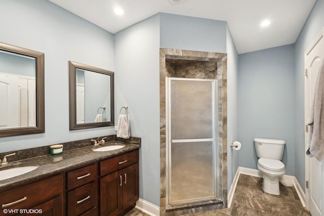 bathroom with a sink, a shower stall, toilet, and double vanity