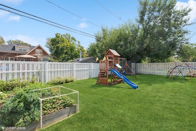 view of jungle gym featuring a lawn, a fenced backyard, and a vegetable garden