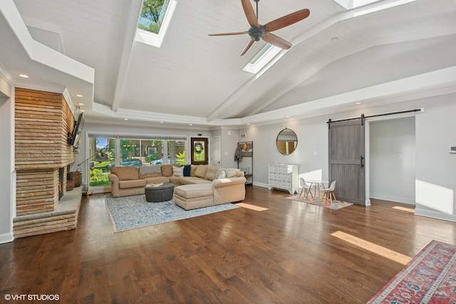 living area with vaulted ceiling with skylight, a ceiling fan, a barn door, baseboards, and recessed lighting