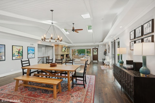 dining room with dark wood-style flooring, baseboards, lofted ceiling with skylight, a barn door, and ceiling fan with notable chandelier