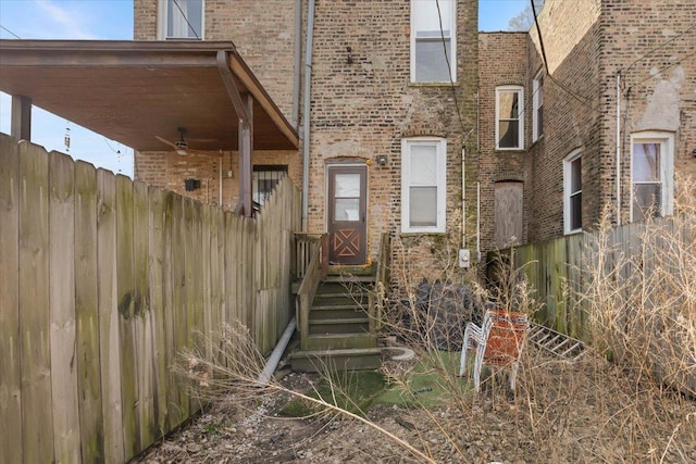 doorway to property featuring fence and brick siding
