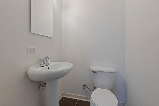 bathroom with tile patterned flooring, baseboards, and toilet
