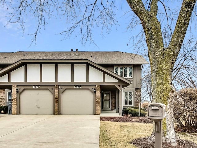 view of front of house featuring a shingled roof, driveway, brick siding, and a garage