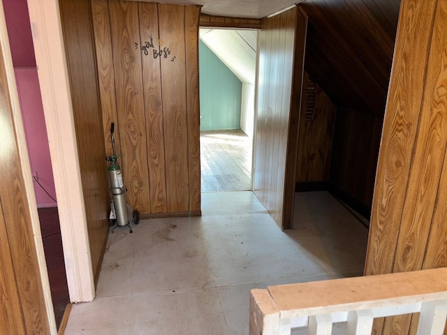 corridor featuring wooden walls and vaulted ceiling