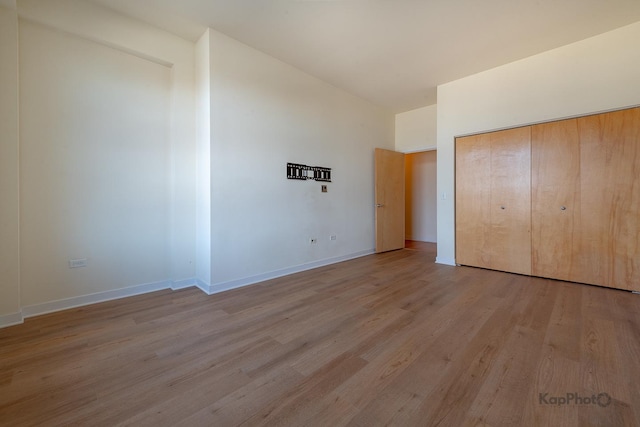 unfurnished bedroom featuring a closet, baseboards, vaulted ceiling, and wood finished floors