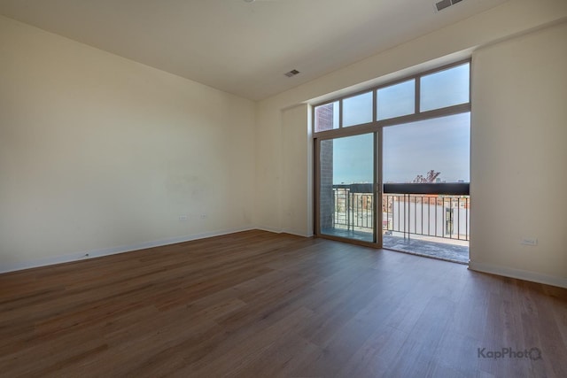 unfurnished room featuring wood finished floors, baseboards, visible vents, and a water view