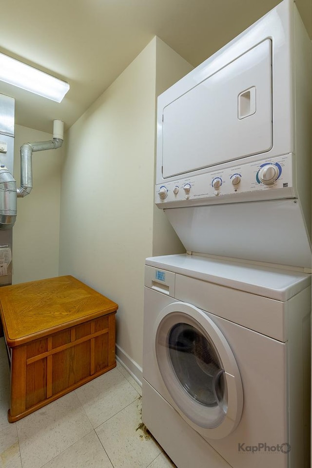 laundry room with baseboards, light tile patterned floors, stacked washer and dryer, and laundry area