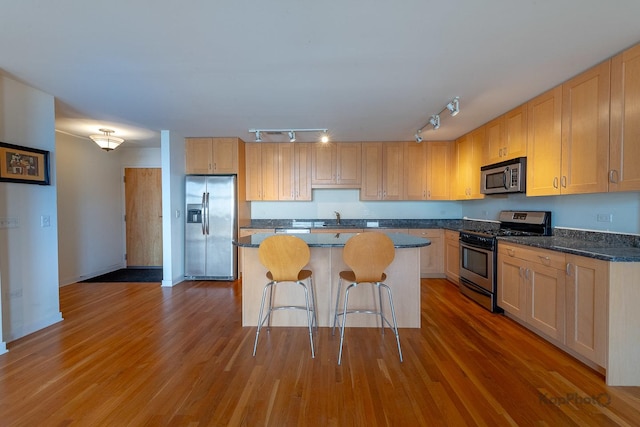 kitchen featuring a center island, wood finished floors, a breakfast bar area, and stainless steel appliances