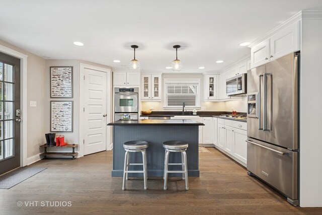 kitchen with glass insert cabinets, white cabinets, recessed lighting, appliances with stainless steel finishes, and dark countertops