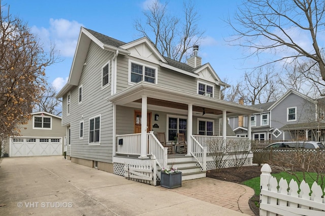 view of front of house with an outbuilding, a detached garage, a porch, fence, and a chimney
