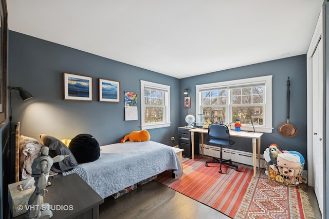 bedroom with a baseboard radiator and wood finished floors