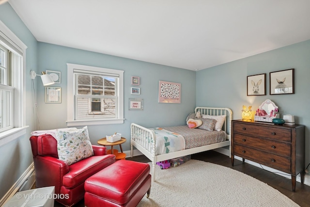 bedroom featuring wood finished floors, baseboards, and multiple windows
