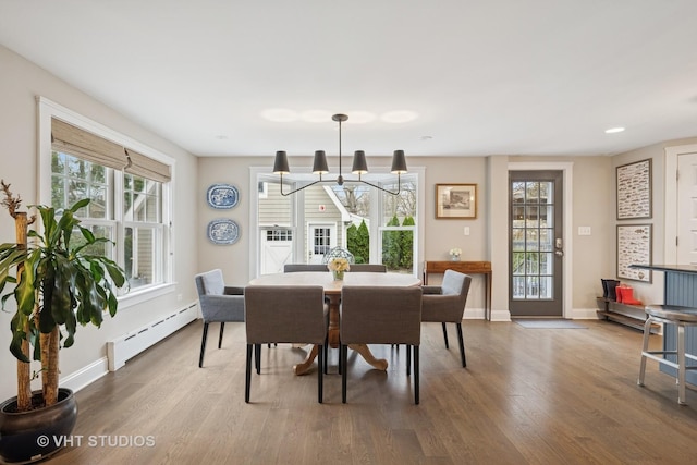 dining room featuring a chandelier, a baseboard radiator, wood finished floors, and baseboards