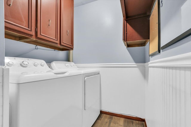 laundry area featuring separate washer and dryer, cabinet space, and wood finished floors