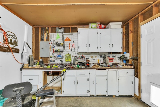 kitchen featuring white cabinets, unfinished concrete floors, and electric panel