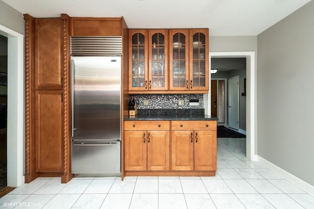1131 S Hamlin Ave, Park Ridge, IL 60068 - kitchen featuring built in refrigerator, brown cabinetry, backsplash, glass insert cabinets, and dark stone counters