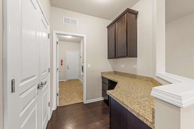 interior space with dark wood-type flooring, visible vents, and baseboards