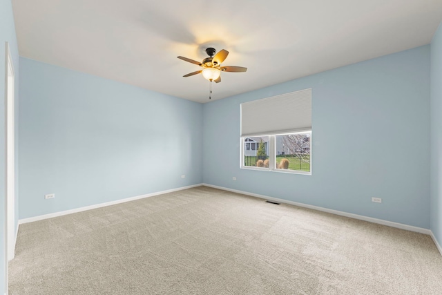 carpeted spare room featuring baseboards, a ceiling fan, and visible vents