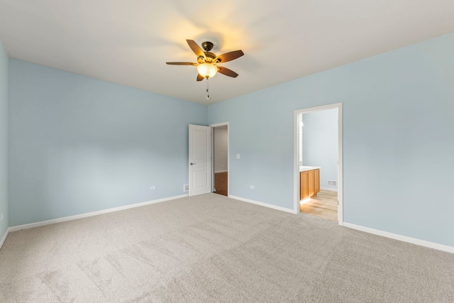 unfurnished bedroom featuring visible vents, baseboards, ceiling fan, ensuite bath, and light colored carpet