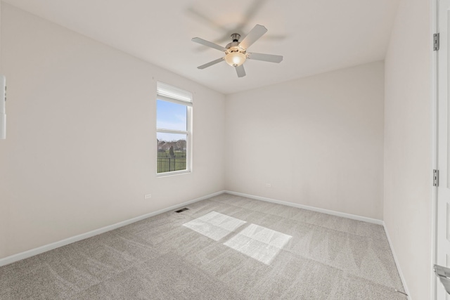 spare room with light carpet, visible vents, baseboards, and ceiling fan