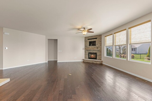 unfurnished living room with visible vents, baseboards, ceiling fan, dark wood-style floors, and a fireplace