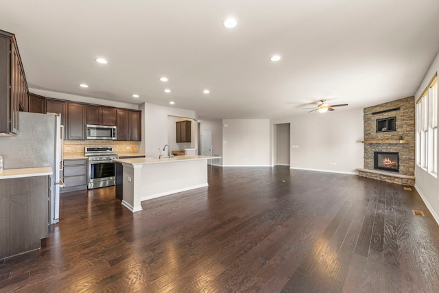 kitchen with a sink, open floor plan, ceiling fan, dark brown cabinetry, and stainless steel appliances