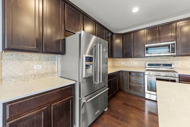 kitchen with dark wood-type flooring, dark brown cabinets, recessed lighting, appliances with stainless steel finishes, and decorative backsplash