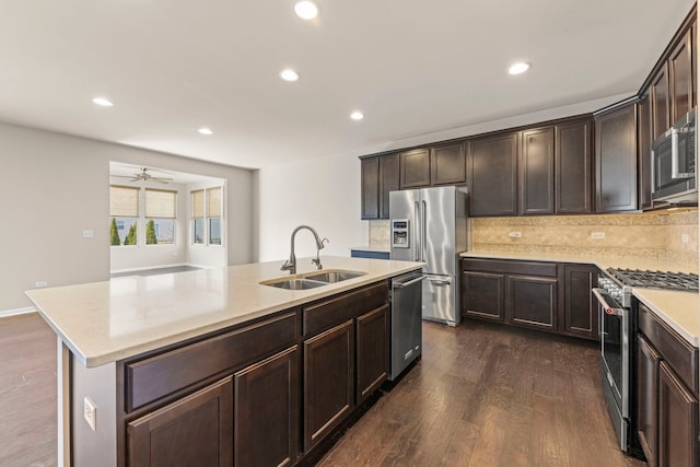 kitchen featuring stainless steel appliances, dark wood-style flooring, a sink, and backsplash