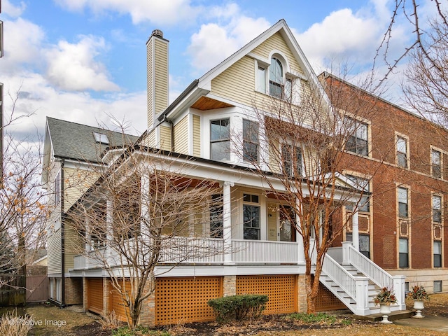view of front of home featuring stairs, a chimney, and covered porch