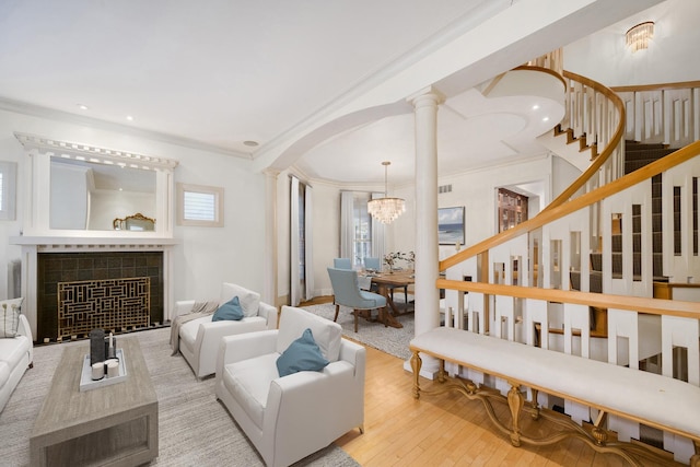 living area featuring arched walkways, ornamental molding, decorative columns, hardwood / wood-style flooring, and a tile fireplace