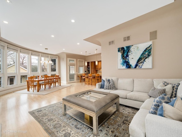 living area featuring visible vents, light wood-style flooring, and recessed lighting
