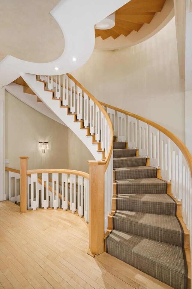 stairway with wood-type flooring, recessed lighting, and a high ceiling