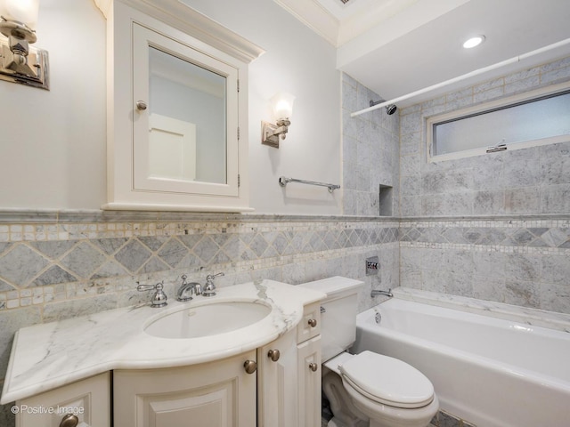 bathroom featuring vanity, shower / tub combination, a wainscoted wall, toilet, and tile walls