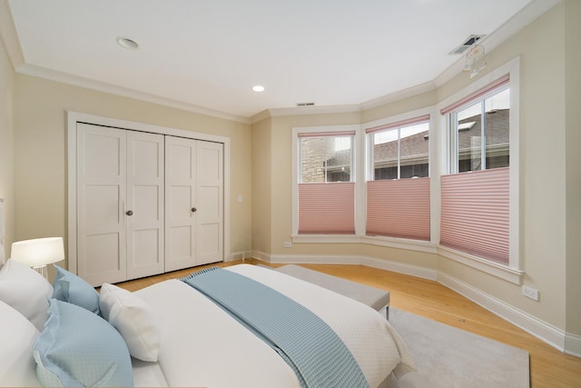 bedroom featuring light wood-type flooring, baseboards, ornamental molding, and visible vents