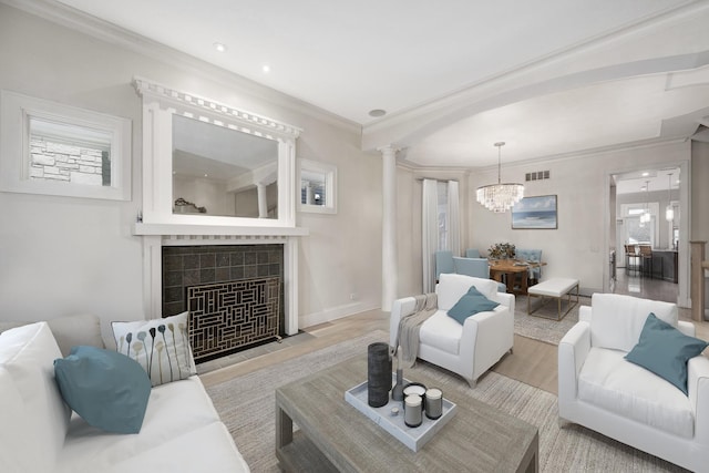 living room featuring ornamental molding, visible vents, wood finished floors, a tile fireplace, and a notable chandelier