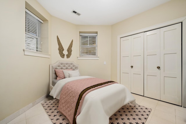 bedroom with visible vents, baseboards, a closet, and light tile patterned floors