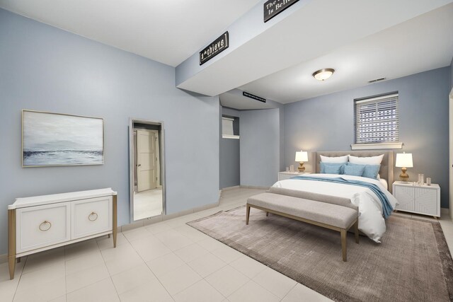 bedroom featuring light tile patterned floors, visible vents, and baseboards