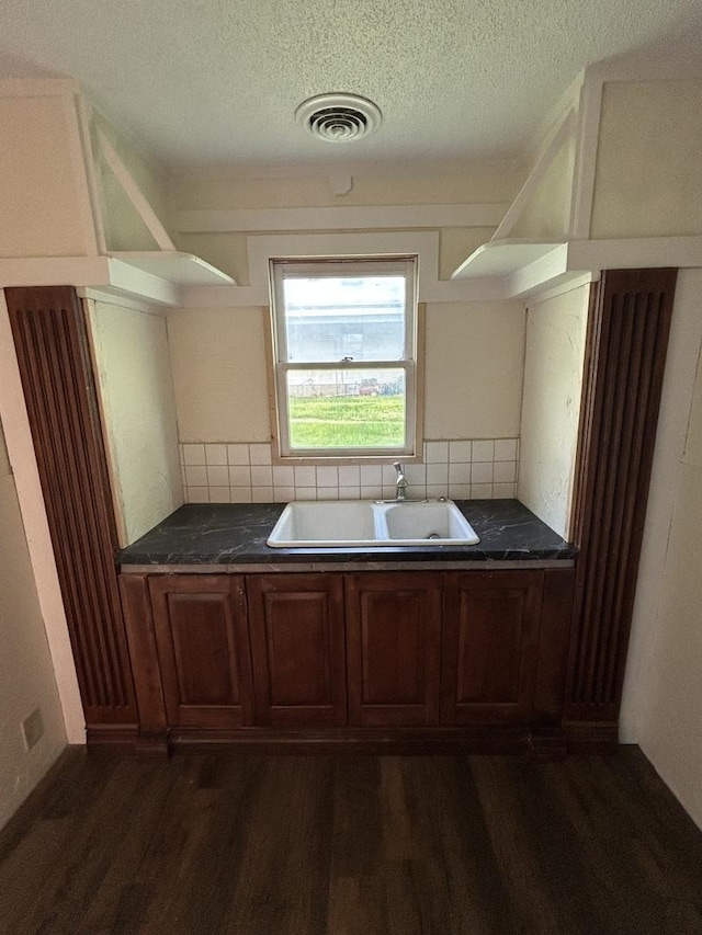 117 N Vermilion St, Potomac, IL 61865 - kitchen with a sink, dark wood-type flooring, a textured ceiling, decorative backsplash, and dark countertops
