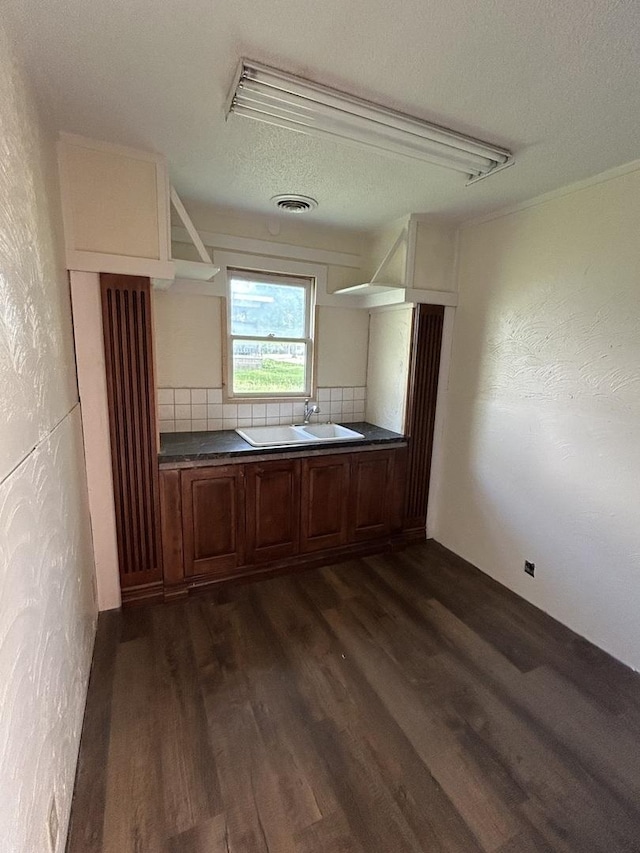 117 N Vermilion St, Potomac, IL 61865 - kitchen with dark wood-style flooring, dark countertops, a textured ceiling, a textured wall, and brown cabinets