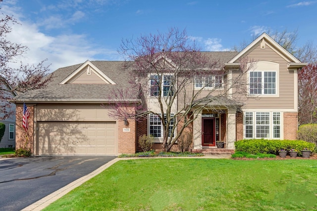 traditional-style house with a front yard, brick siding, driveway, roof with shingles, and an attached garage