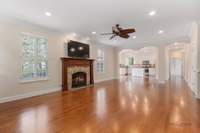 unfurnished living room with ceiling fan, crown molding, recessed lighting, and arched walkways