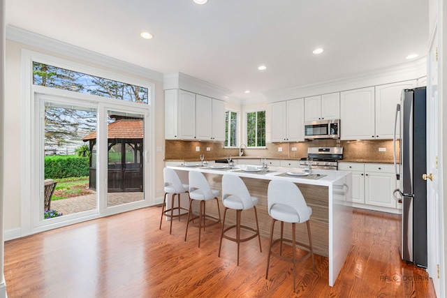 kitchen featuring ornamental molding, light wood-style flooring, white cabinets, and appliances with stainless steel finishes