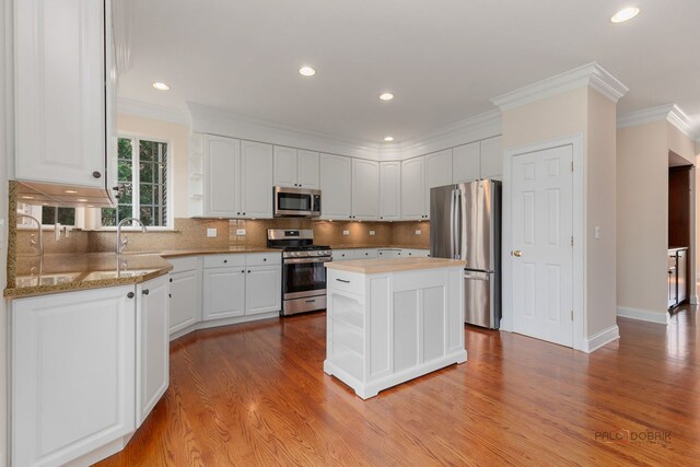 kitchen with appliances with stainless steel finishes, wood finished floors, and white cabinets