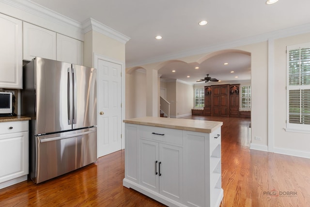 kitchen with arched walkways, freestanding refrigerator, and a healthy amount of sunlight