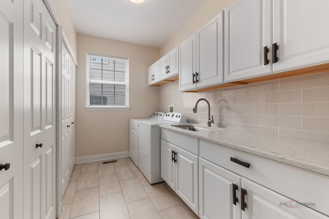 washroom with baseboards, washing machine and dryer, cabinet space, and a sink