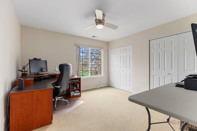 carpeted home office featuring baseboards, visible vents, and ceiling fan