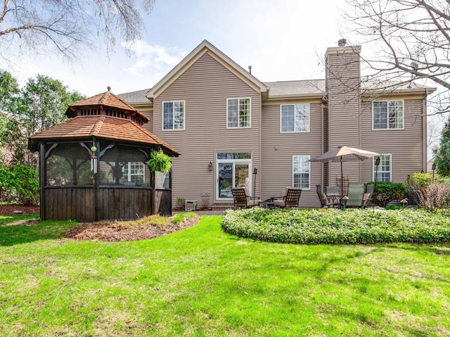 rear view of property featuring a gazebo, a yard, and a chimney