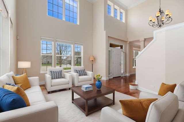 living area with an inviting chandelier, wood finished floors, baseboards, and a high ceiling