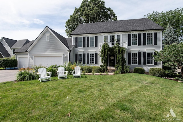 colonial house with a front yard, a balcony, driveway, and an attached garage